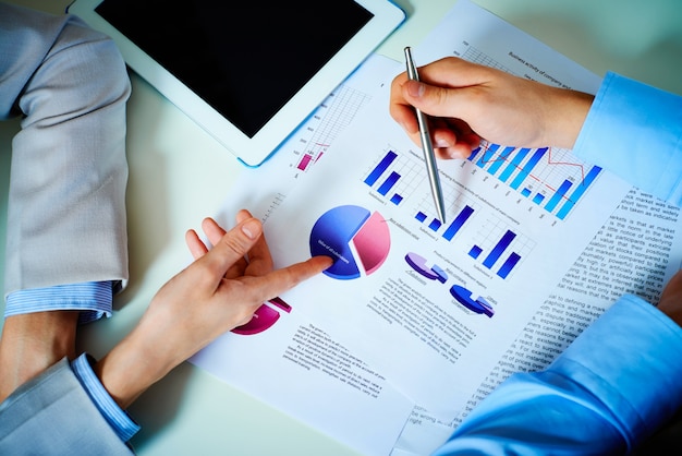 Close-up of hands with financial charts at business meeting