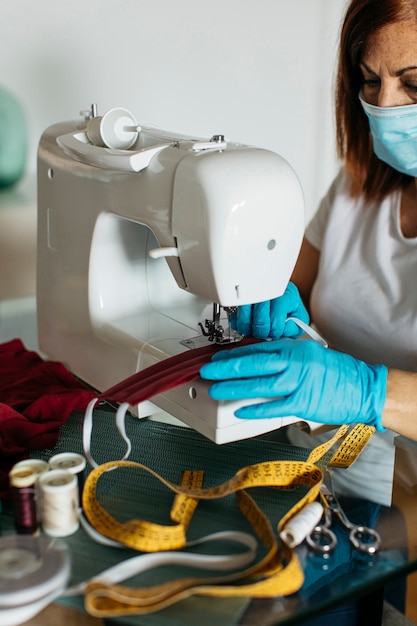 Free photo close-up of hands with gloves sewing cloth face masks