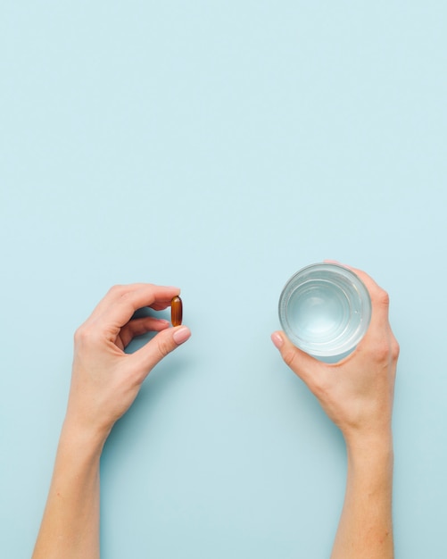 Close-up hands with pill and water