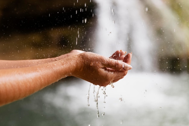 Close up on hands of young adult by the waterfall