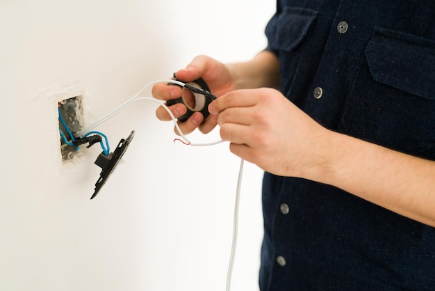 Free photo close up of the hands of a young man hands repairing the broken switch and doing home renovations