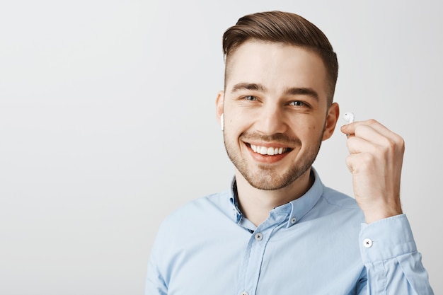 Close-up of handsome young man take-off earphone to hear what you say