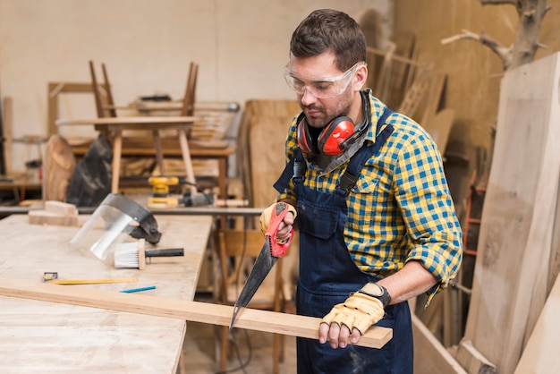 Free Photo close-up of a handyman sawing long wooden plank