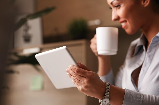 Close up of happy entrepreneur enjoying in coffee break while browsing the Internet on touchpad