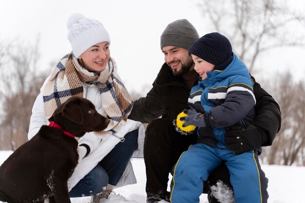 Free photo close up on happy family playing in the snow with dog