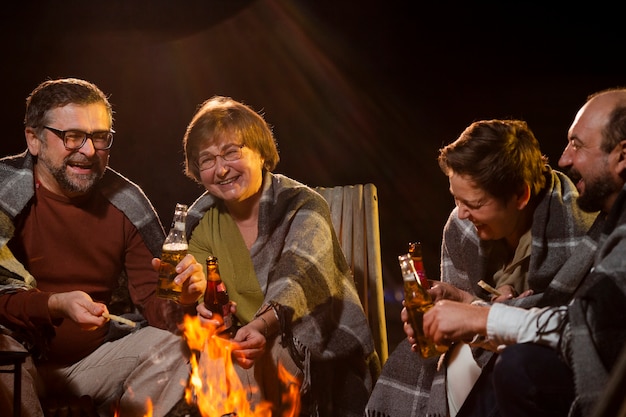 Close up happy people sitting around fire