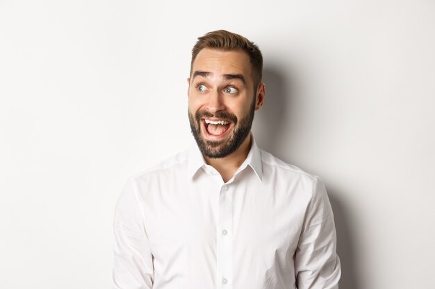 Close-up of happy and surprised man looking left with excitement   