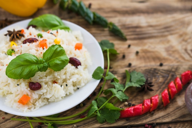 Free Photo close-up of healthy rice; basil leaves; on plate with parsley and chili peppers on blurred background