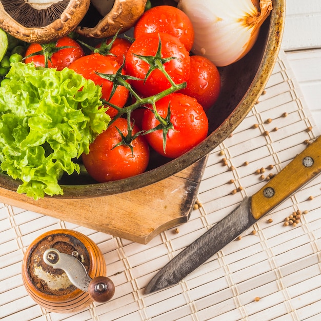 Close-up of healthy vegetable; knife; spice grinder on placemat