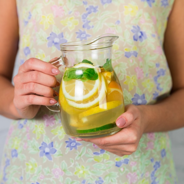 Free photo close up homemade lemonade jug held by woman