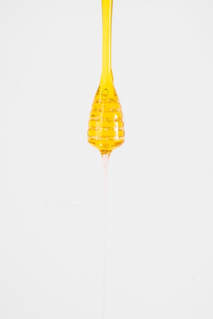 Free photo close-up of honey dripping from dipper on white background