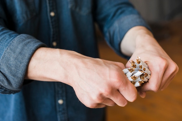 Free Photo close-up of human hand breaking bundle of cigarettes