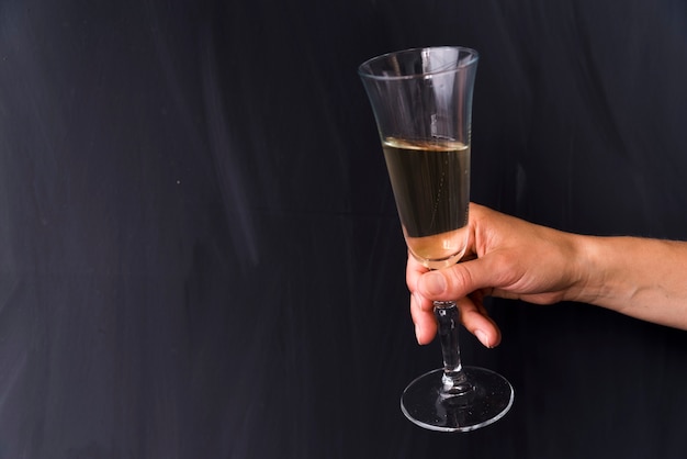 Free Photo close-up of human hand holding alcoholic drink glass on black backdrop