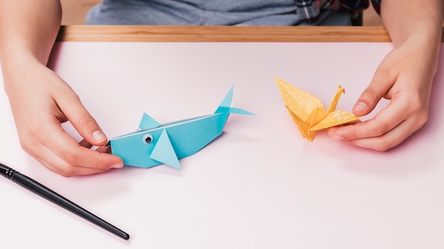 Close-up of human hand holding origami fish and bird