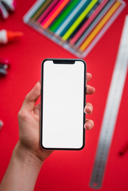 Free photo close-up of a human hand holding smartphone with blank white display over blurry backdrop