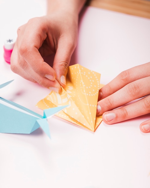 Close-up of a human hand making origami bird