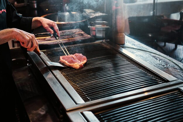 Close-up image of a cooking delicious meat steak on a grill in a restaurant kitchen.