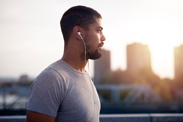 Close up image of fit young sportsman wearing earphones focusing for his training