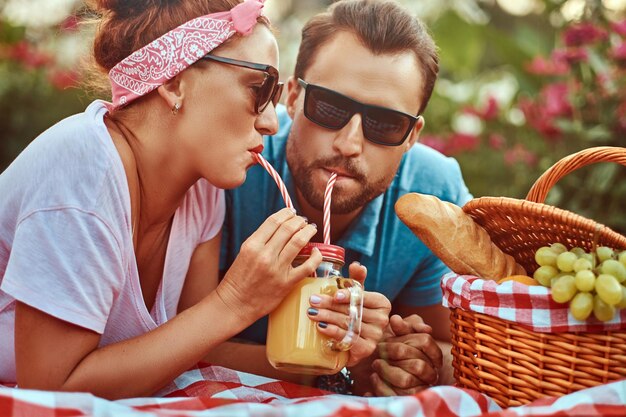 Close-up image of a happy middle age couple during romantic dating outdoors, enjoying a picnic while lying on a blanket in the park.