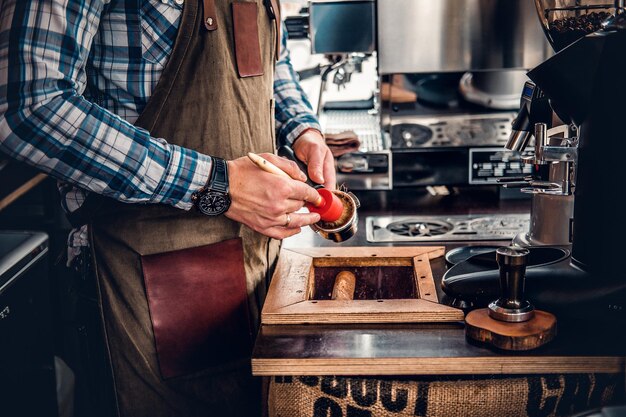 Close up image of a man cleans coffee machine with a tassel.