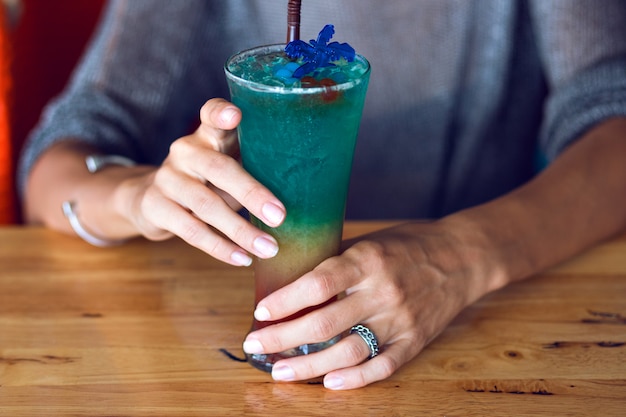 Close up image of woman holding tasty colorful rainbow tasty alcohol sweet cocktail, summer party time.