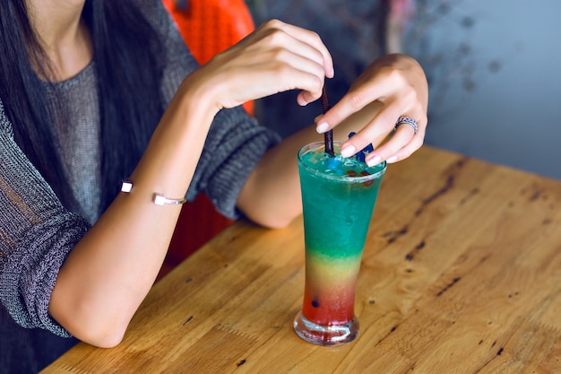 Close up image of woman holding tasty colorful rainbow tasty alcohol sweet cocktail, summer party time.