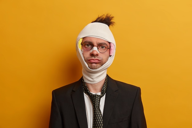 Close up on injured man with dark bruise under eyes and brain concussion, wears bandage