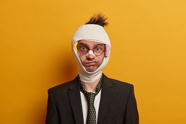 Close up on injured man with dark bruise under eyes and brain concussion, wears bandage