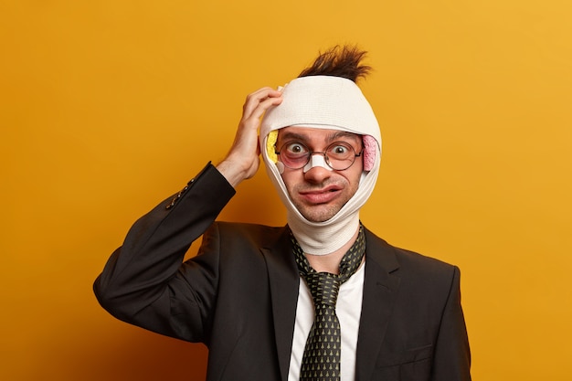 Close up on injured man with dark bruise under eyes and brain concussion, wears bandage