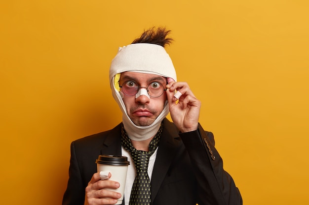 Close up on injured man with dark bruise under eyes and brain concussion, wears bandage