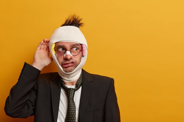 Close up on injured man with dark bruise under eyes and brain concussion, wears bandage