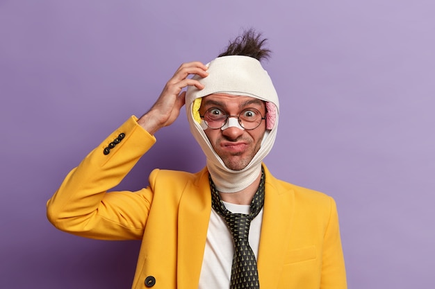 Close up on injured man with dark bruise under eyes and brain concussion, wears bandage