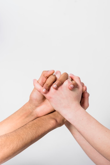 Close-up of interracial couple holding each other's hand against white background