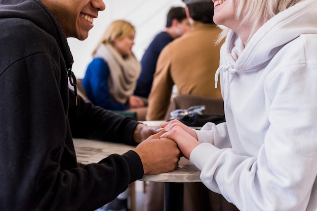 Close-up of interracial smiling young couple holding each other hands