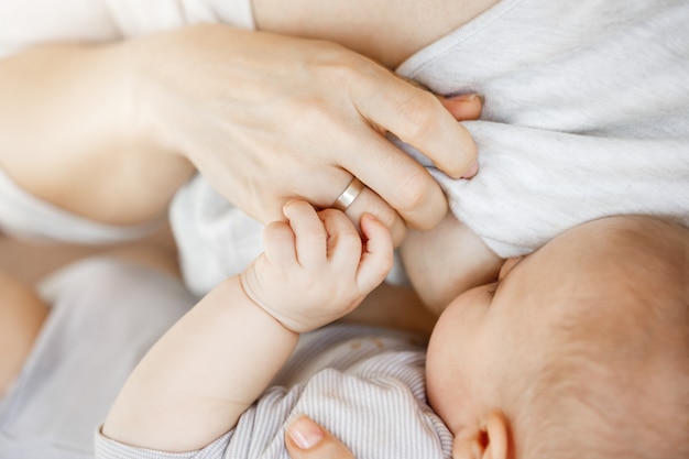 Close up of intimate moment mother lactating her newborn son. Scene of innocence and protection. Family, motherhood and lifestyle concept.