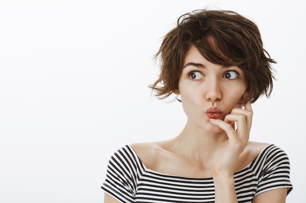 Close-up of intrigued and excited woman pouting, looking left curious