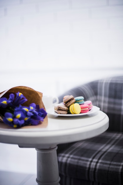 Free photo close-up of an iris bouquet with colorful macaroons on white plate