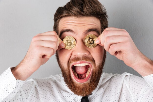 Close up of a joyful businessman with bitcoins in his eyes