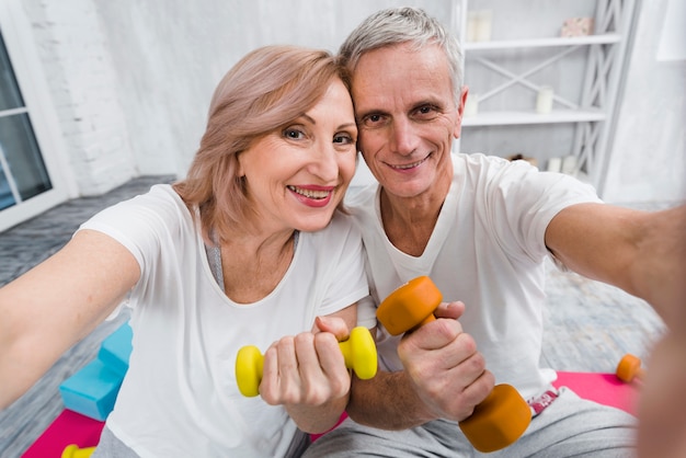 Free Photo close-up of joyful loving senior couple exercising with dumbbells