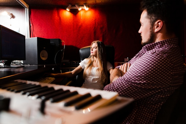 Close-up keyboard and people mastering the songs