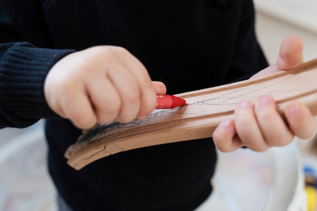 Free Photo close up kid drawing on wooden piece