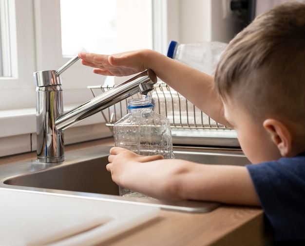 Free photo close up kid filling bottle with water