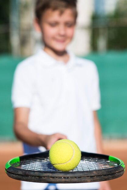 Close-up kid holding a ball on the racket