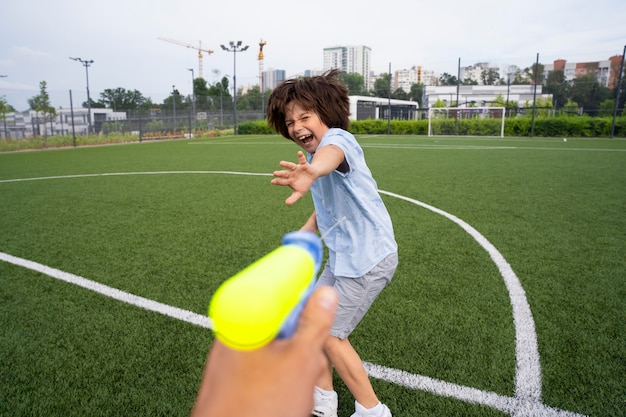 Free photo close up kids playing with water gun on field