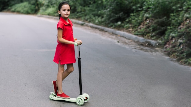 Free photo close-up of a little girl standing on push scooter