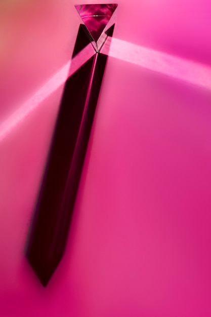 Free photo close-up of long crystal prism with shadow on pink background