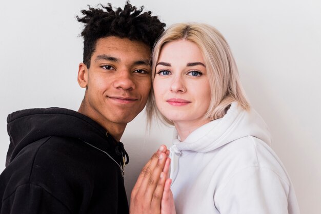 Close-up of loving interracial young couple looking at camera