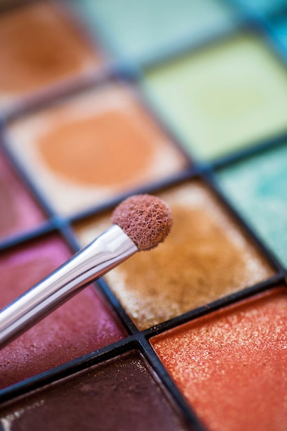 Free photo close-up of makeup brush over colorful eye shadow palette