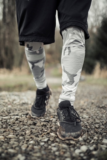 Free photo close-up of male athlete's feet running on gravel trail