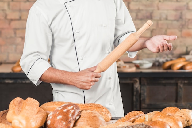 Close-up of male baker standing behind the table holding rolling pin